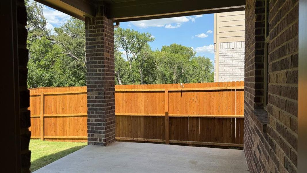 Covered patio with a concrete slab, brick support columns, and a full privacy fence Covered patio with a concrete slab, brick support columns, and a full privacy fence