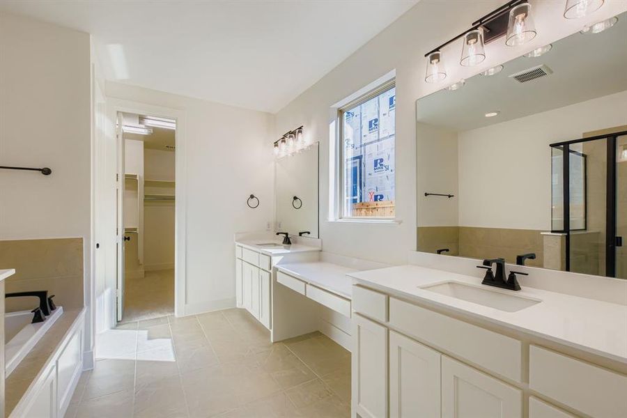 Full bathroom with a stall shower, two vanities, light tile patterned floors, a garden tub, and a spacious closet