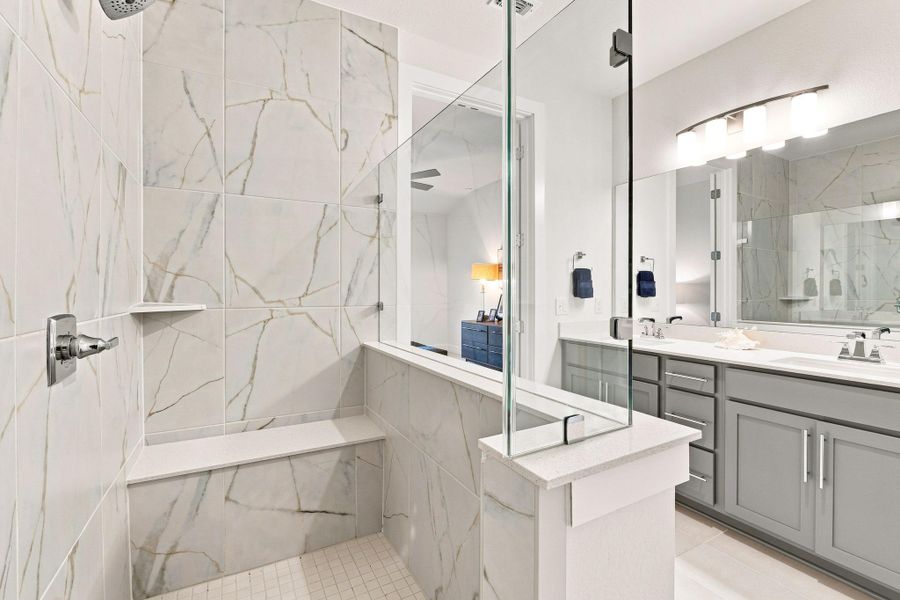 Spa-inspired primary shower featuring an upgraded 3/8" frameless clear glass enclosure, built-in tile bench, and floor-to-ceiling tile surround. Spa-inspired primary shower featuring an upgraded 3/8" frameless clear glass enclosure, built-in tile bench, and floor-to-ceiling tile surround.