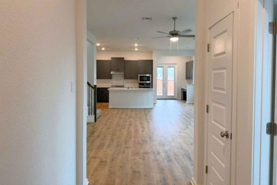 Kitchen with open floor plan, light wood finished floors, light countertops, dark wood finish cabinets, and an island with sink