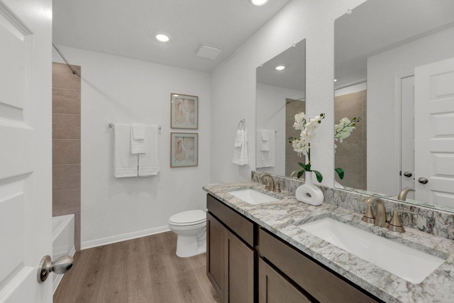 Bathroom featuring light wood-style flooring, double vanity, recessed lighting, and washtub / shower combination Bathroom featuring light wood-style flooring, double vanity, recessed lighting, and washtub / shower combination