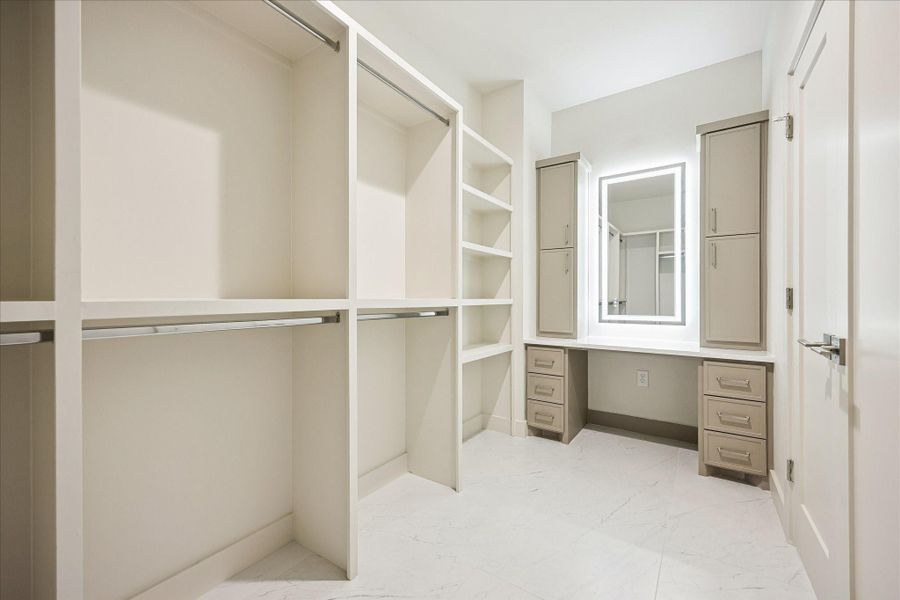 This is one of two custom walk-in closets in the owner’s suite. This thoughtfully designed space offers built-in shelving, ample hanging space and a dedicated vanity with a backlit mirror that makes getting ready feel a little more luxurious.