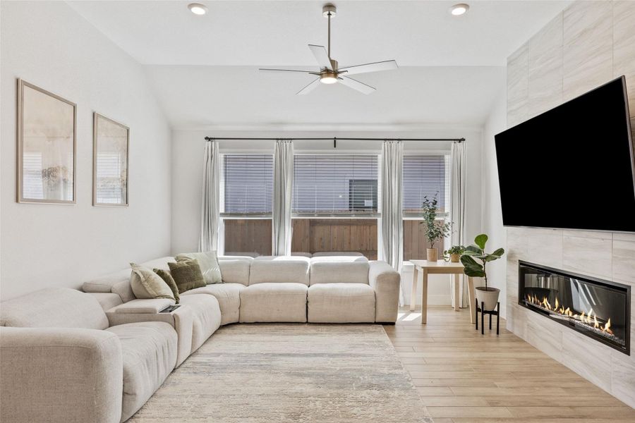 The living room is anchored by a sleek electric fireplace with tile surround,