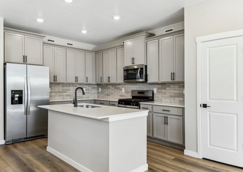 The kitchen has stainless steel appliances and plank flooring.