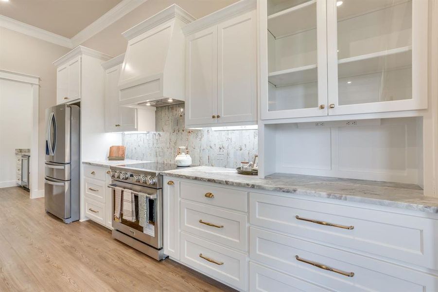 Gourmet kitchen featuring white shaker cabinetry, stainless steel appliances, a tile backsplash, light-toned countertops, and wood-finish flooring