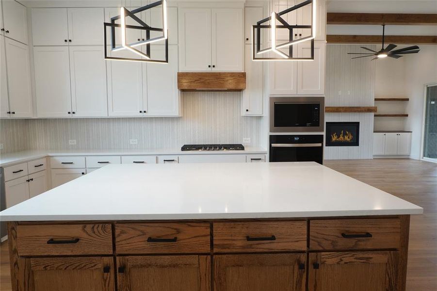 Kitchen with beamed ceiling, white cabinetry, a kitchen island, and appliances with stainless steel finishes