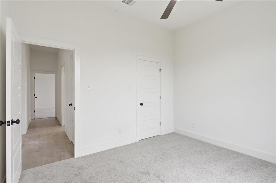 Bedroom featuring light gray carpet, crisp white walls, and a contemporary ceiling fan Bedroom featuring light gray carpet, crisp white walls, and a contemporary ceiling fan
