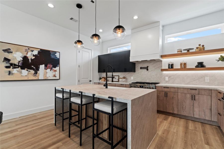 This kitchen is a showstopper with its double waterfall island wrapped in 5cm Taj Mahal quartz, accented by modern pendant lighting and fluted wood details—it’s all in the details with this home. This kitchen is a showstopper with its double waterfall island wrapped in 5cm Taj Mahal quartz, accented by modern pendant lighting and fluted wood details—it’s all in the details with this home.