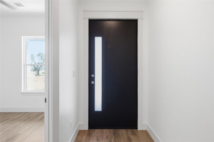 A sleek, contemporary black entry door with a frosted glass insert welcomes you into a bright interior. A sleek, contemporary black entry door with a frosted glass insert welcomes you into a bright interior.