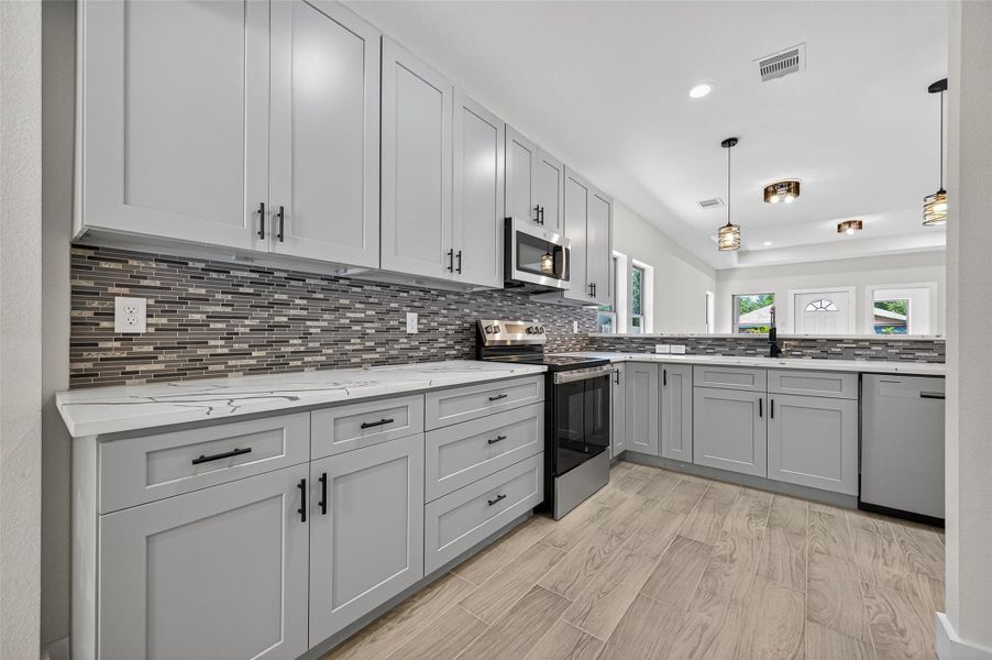 This kitchen features modern gray cabinetry, a stylish tile backsplash, and sleek stainless steel appliances. The open layout and ample counter space are perfect for cooking and entertaining. This kitchen features modern gray cabinetry, a stylish tile backsplash, and sleek stainless steel appliances. The open layout and ample counter space are perfect for cooking and entertaining.