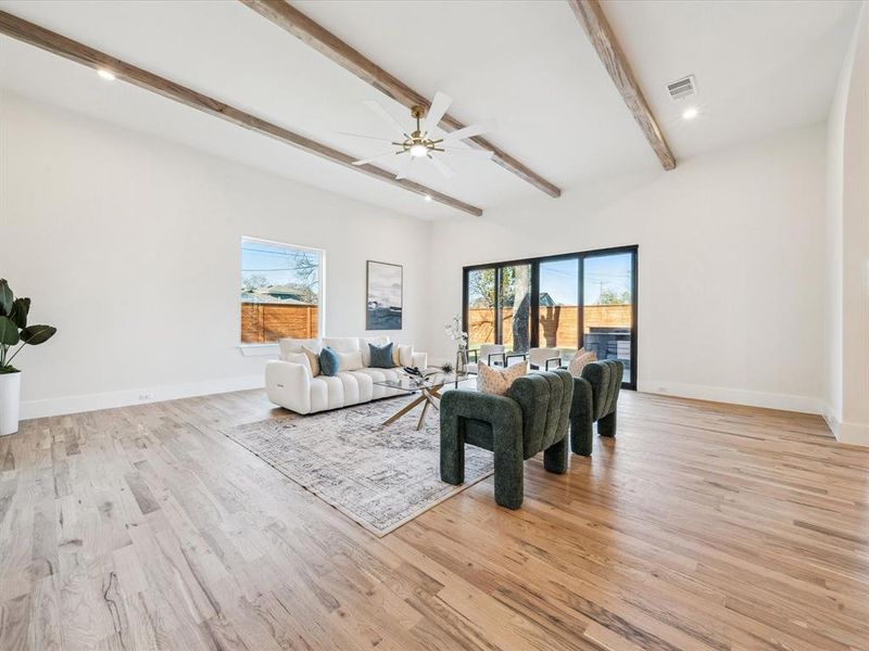 Living room featuring a wealth of natural light, light hardwood / wood-style flooring, beamed ceiling, and ceiling fan