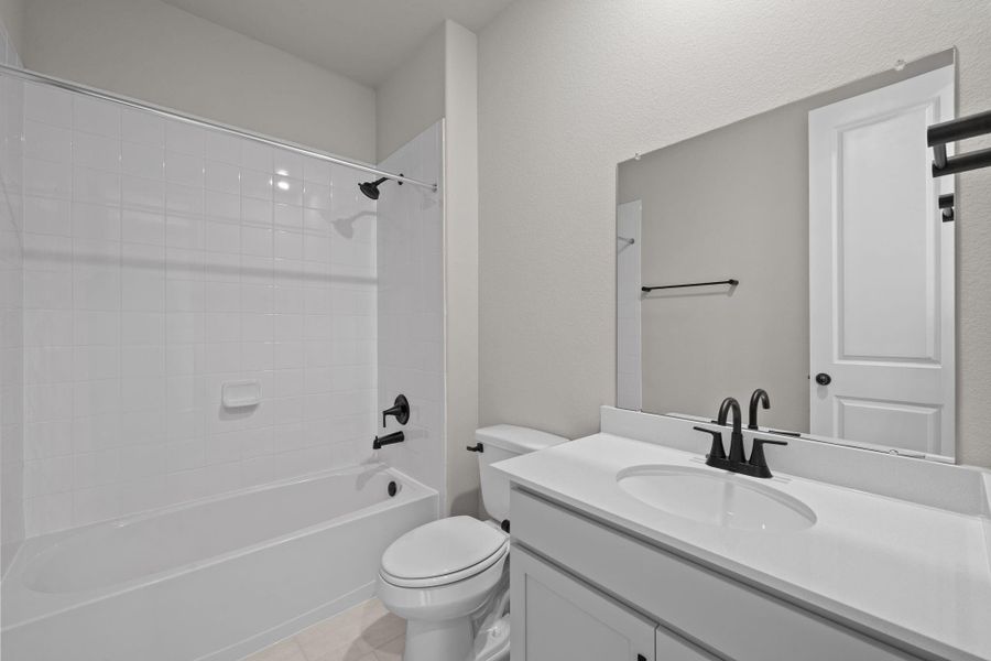 The secondary bath features tile flooring, white cabinetry and light countertops and a shower/tub combo. Perfect for accommodating any visiting family and friends.