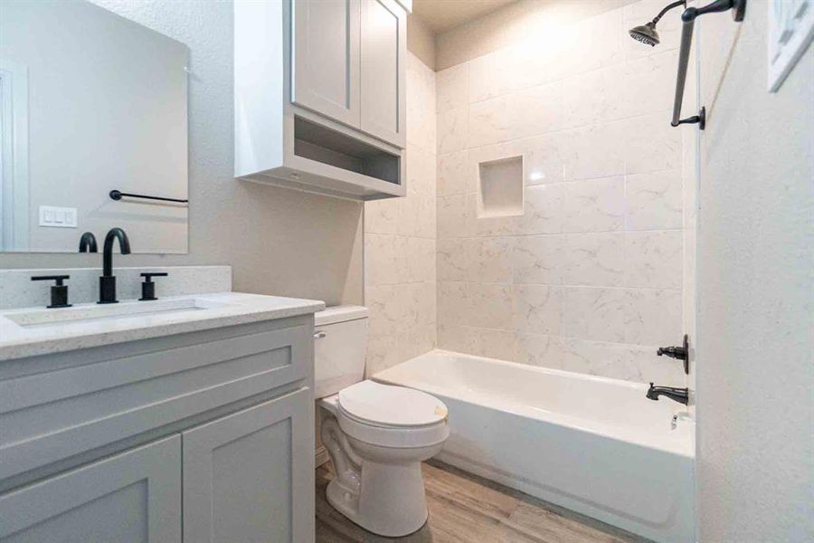 Full bath with shower / bathtub combination, vanity, and light wood-style flooring