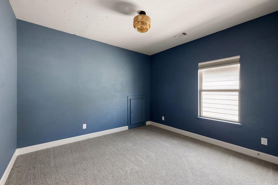 A quiet space for slumber, this bedroom offers plush carpet flooring and a window with blinds for privacy.
