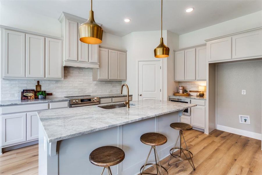 Kitchen featuring light stone countertops, hanging light fixtures, and sink