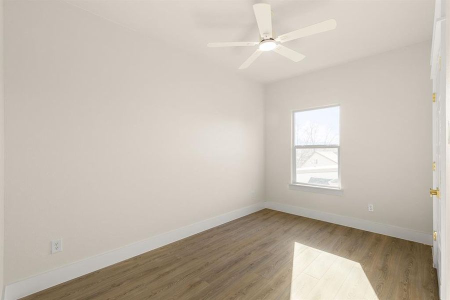 Spare room featuring wood finished floors, a ceiling fan, and baseboards