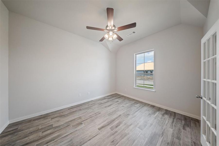 Spare room featuring vaulted ceiling, wood finished floors, and ceiling fan