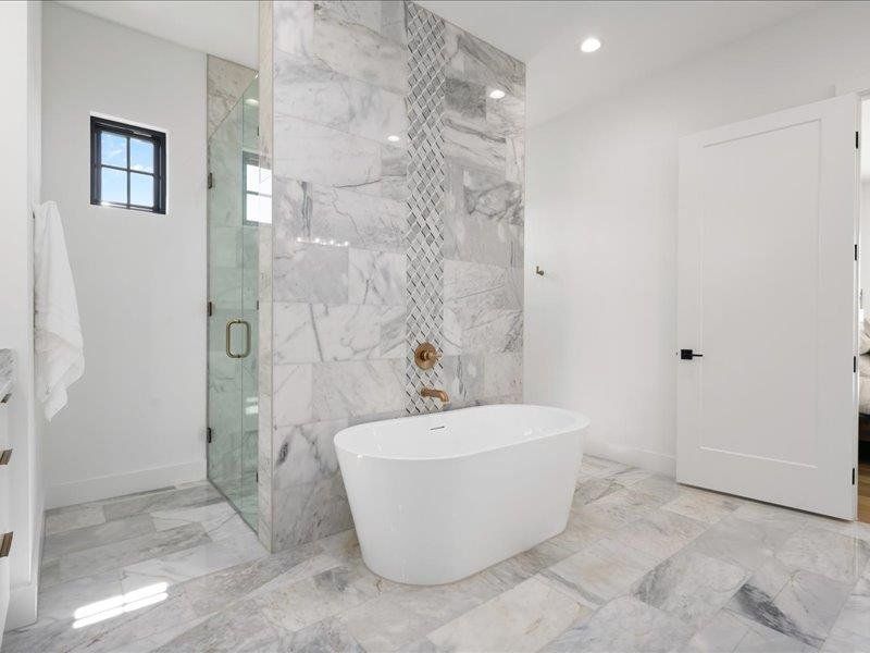 Bathroom with marble tiled flooring, a shower stall, a freestanding bath, baseboards, and recessed lighting