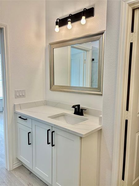 Bathroom featuring vanity, light wood-style flooring, and a textured wall