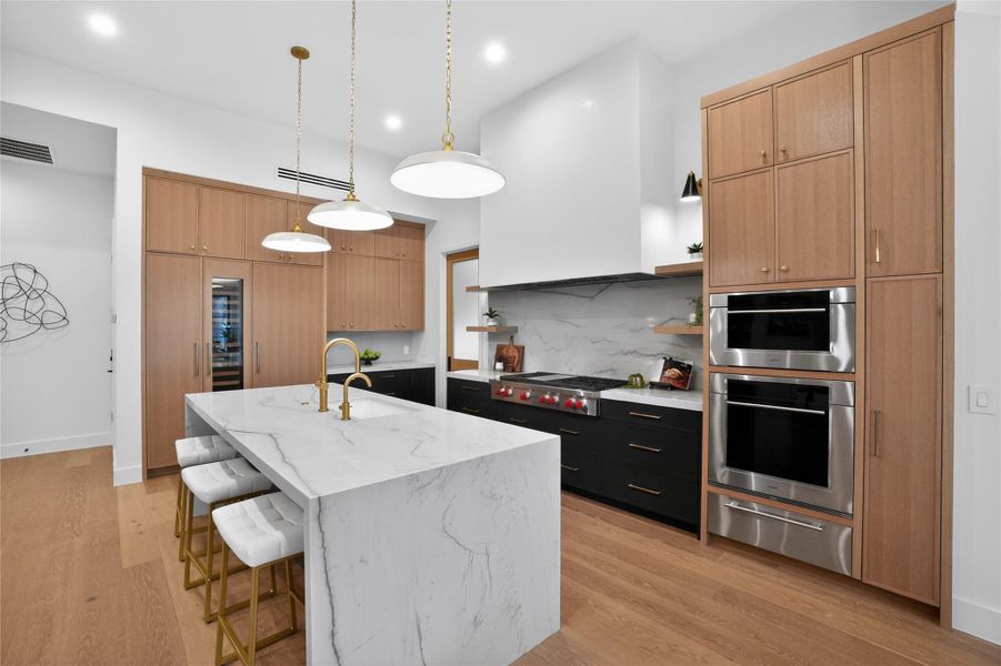Culinary excellence awaits in this modern kitchen with golden accents and marble-clad island.