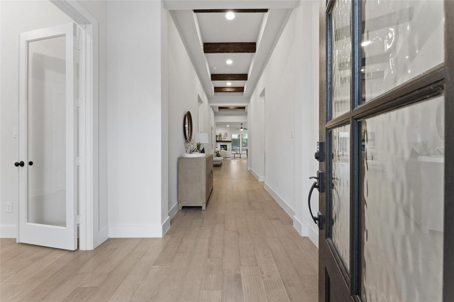 Entryway featuring a decorative glass-paned door, wood-finish flooring, recessed lighting, white baseboards, and ceiling beams