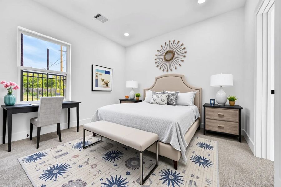 Bright and spacious bedroom with modern decor, featuring a comfortable bed, stylish side tables, a cozy rug, and a functional desk area by the window.