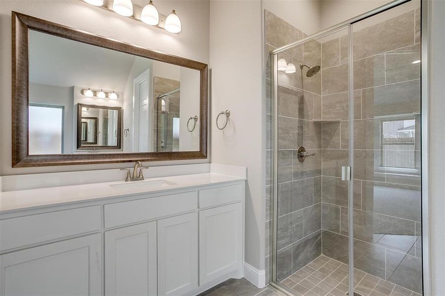 Bathroom featuring a shower with shower door and vanity