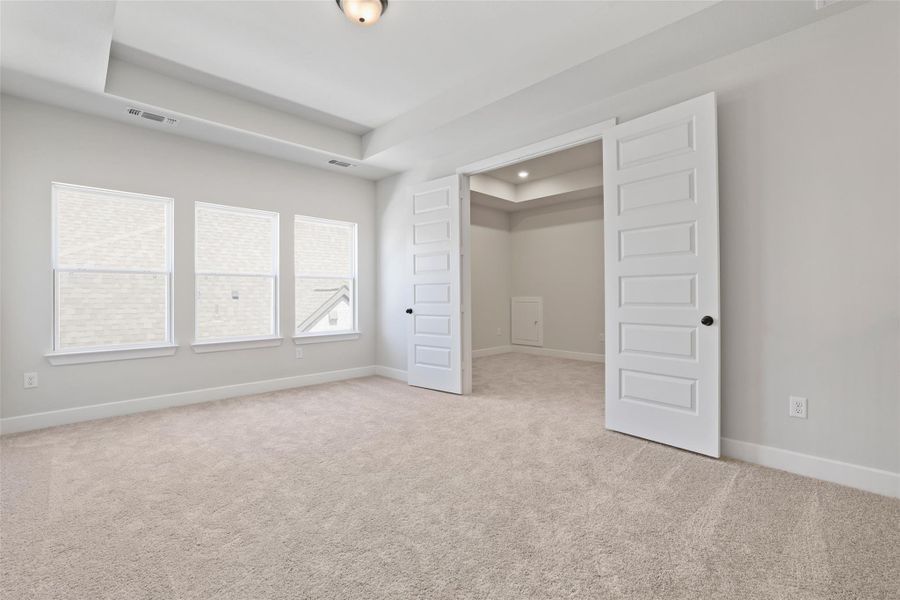 Unfurnished bedroom featuring a tray ceiling and light carpet Unfurnished bedroom featuring a tray ceiling and light carpet