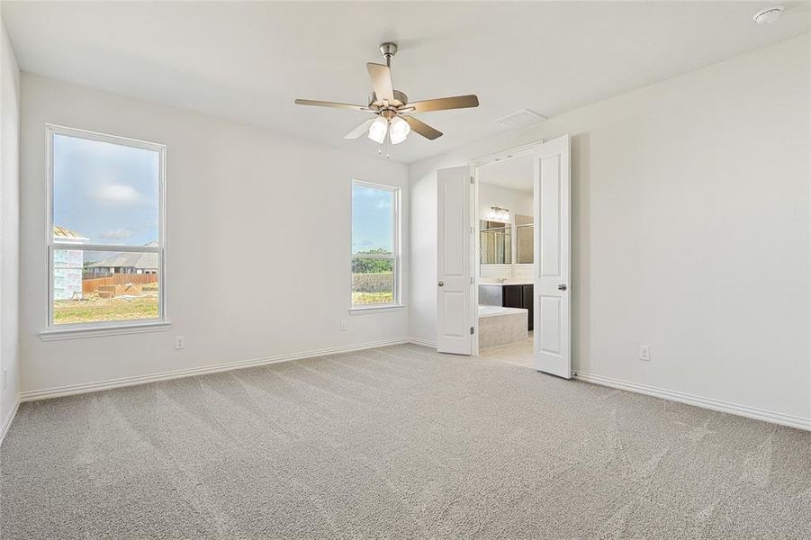 Unfurnished bedroom featuring light colored carpet, connected bathroom, and ceiling fan