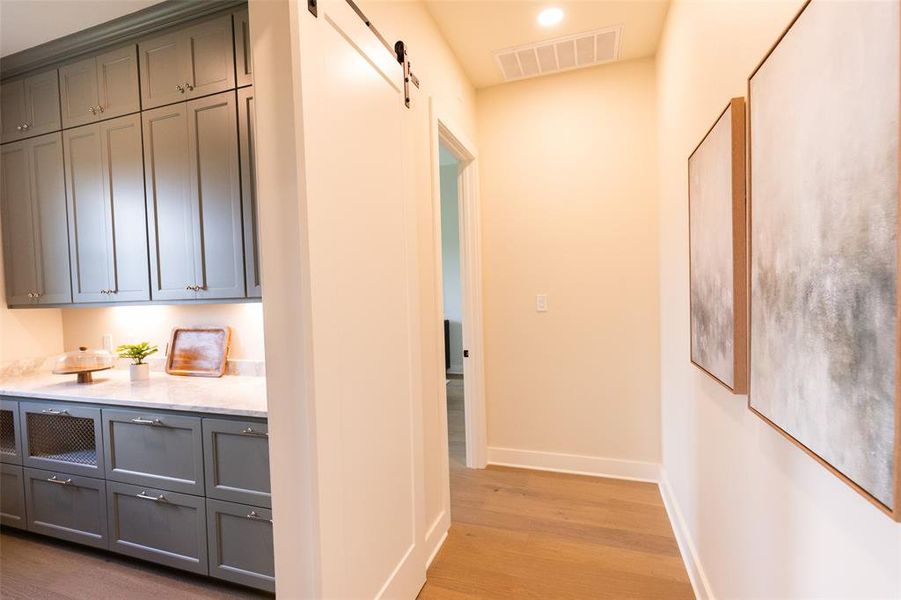 Built-in cabinetry with marble-look countertops, under-cabinet lighting, and a barn door entry