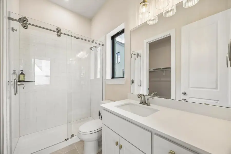EN SUITE BATH INCLUDES A GLASS-ENCLOSED SHOWER WITH SUBWAY TILE, QUARTZ COUNTERTOP, LARGE MIRROR, AND A WALK-IN CLOSET. EN SUITE BATH INCLUDES A GLASS-ENCLOSED SHOWER WITH SUBWAY TILE, QUARTZ COUNTERTOP, LARGE MIRROR, AND A WALK-IN CLOSET.