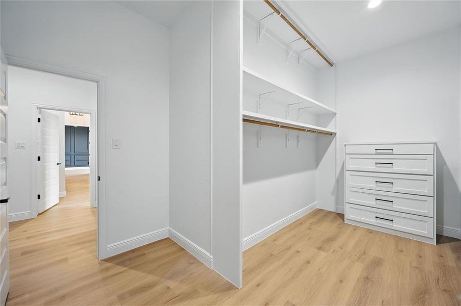 Spacious closet with light wood-style flooring Spacious closet with light wood-style flooring