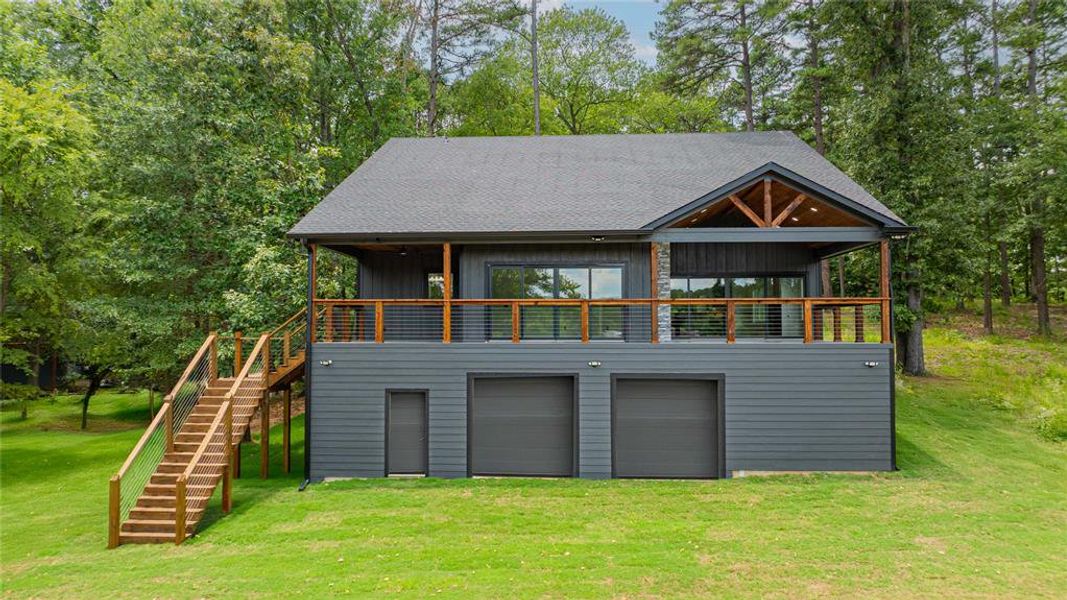 Back of house with stairway, a yard, driveway, and view of scattered trees Back of house with stairway, a yard, driveway, and view of scattered trees
