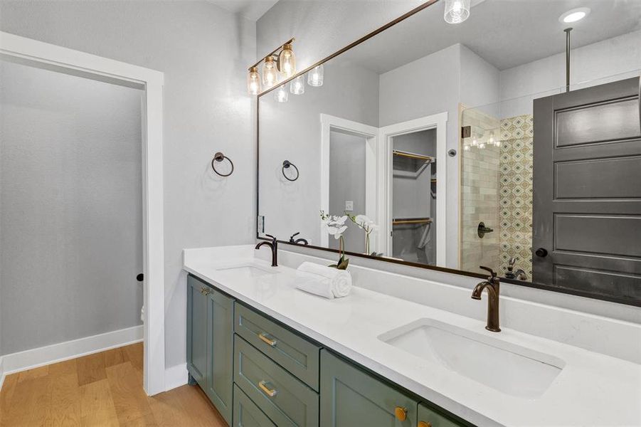 Bathroom with a stall shower, double vanity, light wood-style floors, and a walk in closet Bathroom with a stall shower, double vanity, light wood-style floors, and a walk in closet