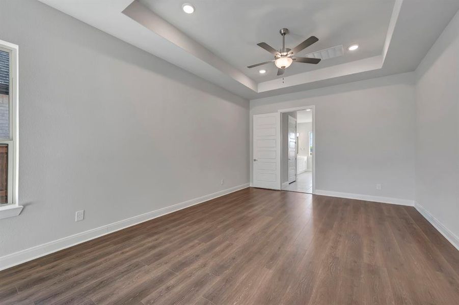 Spare room featuring a ceiling fan, dark wood-style floors, recessed lighting, and a raised ceiling