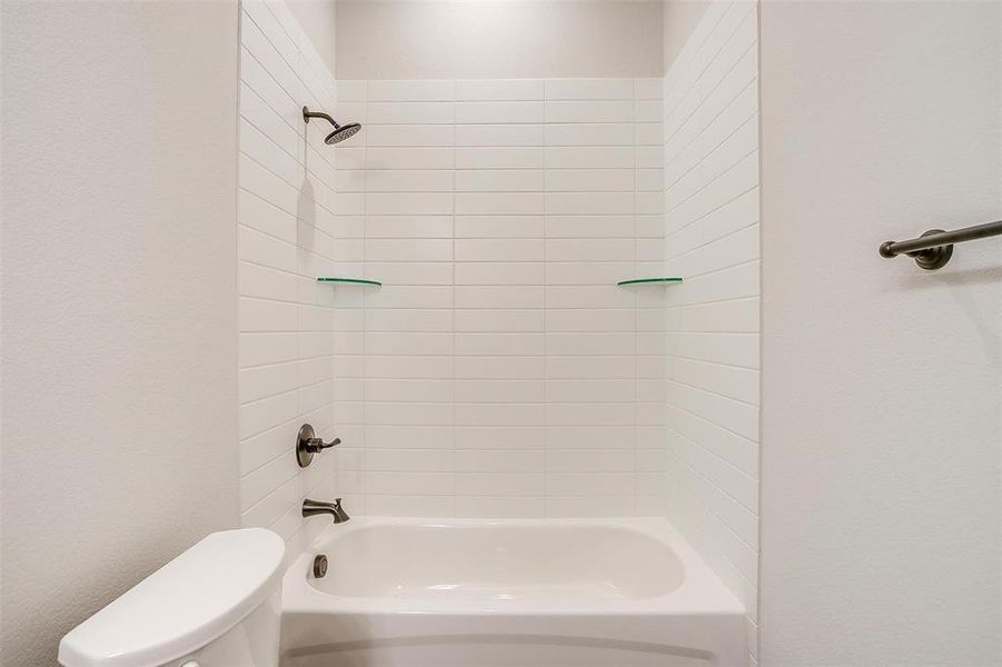 Bathroom with tiled shower / bath combo and toilet