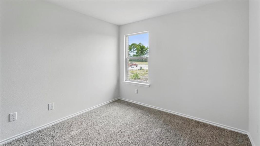 Neutral tone walls with a single window, white trim, and gray speckled carpeting