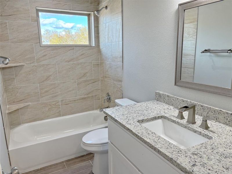 Bathroom with  shower combination, vanity, a textured wall, and wood finish floors