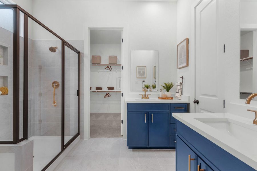 Full bathroom with a stall shower, two vanities, and a walk in closet