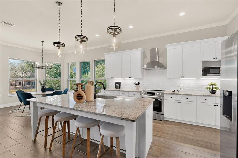 Modern kitchen featuring a large central island with seating, white shaker-style cabinetry, stainless steel appliances, and a tile backsplash