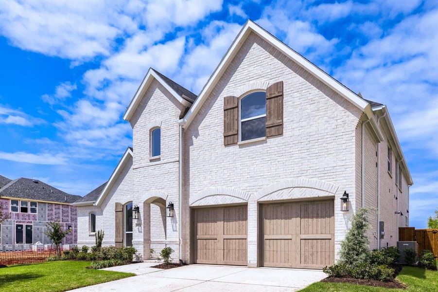 Two-story residence featuring a white brick exterior, gabled rooflines, and decorative wood shutters Two-story residence featuring a white brick exterior, gabled rooflines, and decorative wood shutters