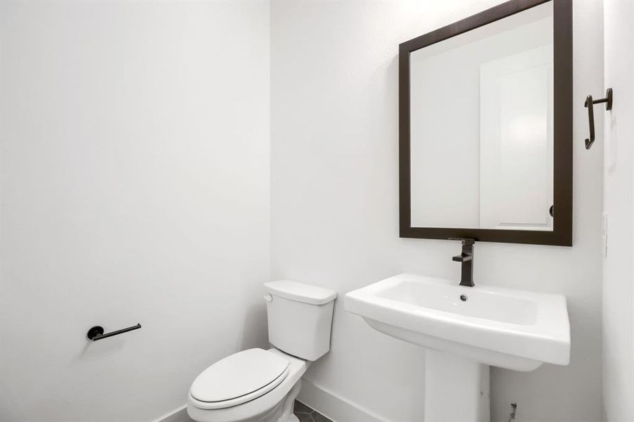 Pedestal sink with dark bronze faucet and framed mirror