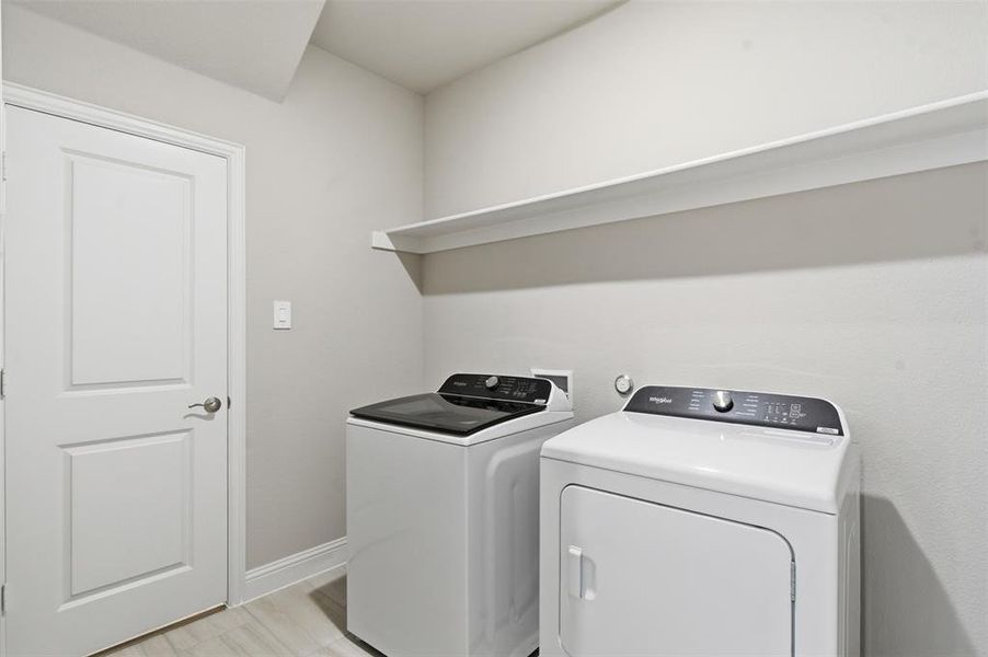 Dedicated laundry area featuring a washer, dryer, and an overhead shelf for storage