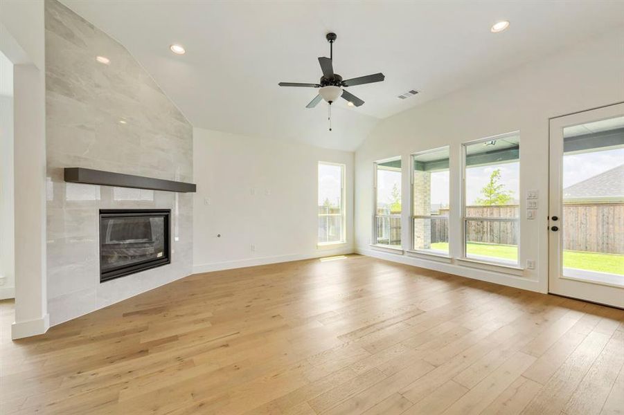 Spacious interior with vaulted ceilings, light wood-finish flooring, and a modern fireplace with a dark mantel Spacious interior with vaulted ceilings, light wood-finish flooring, and a modern fireplace with a dark mantel