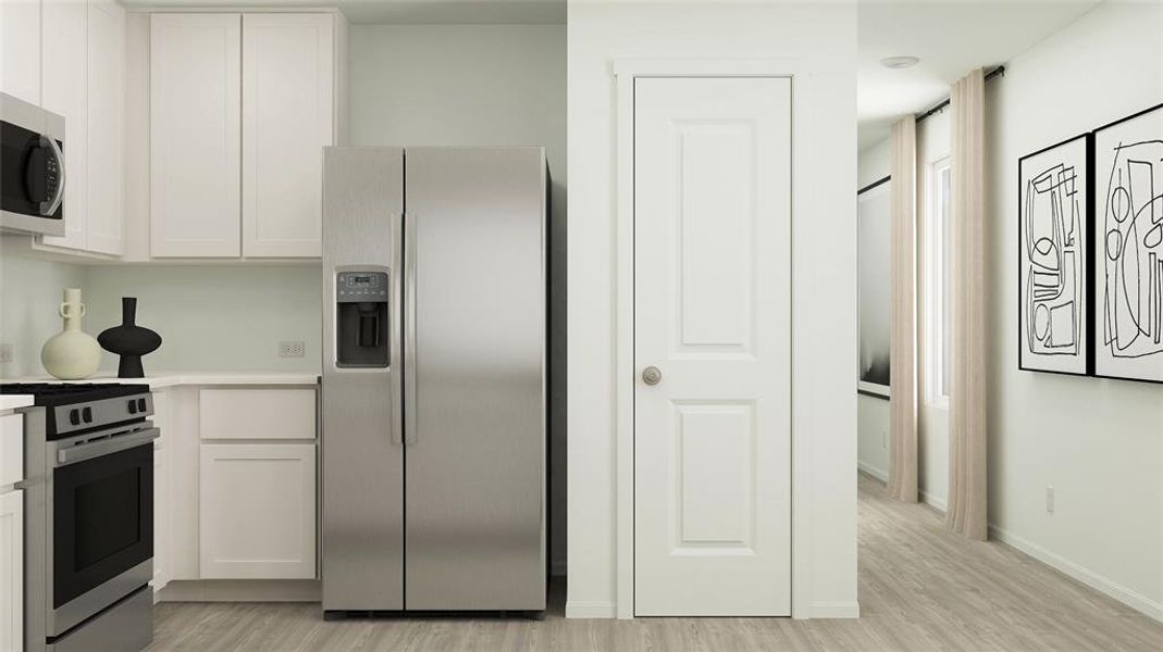 Kitchen featuring light hardwood / wood-style flooring, white cabinets, and appliances with stainless steel finishes