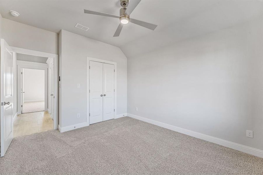 Unfurnished bedroom with light carpet, lofted ceiling, a ceiling fan, and a closet