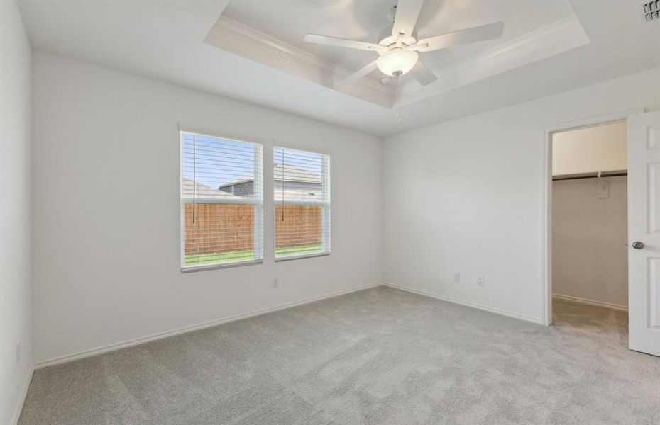 Spacious owner's suite with large windows and elegant tray ceiling *real home pictured