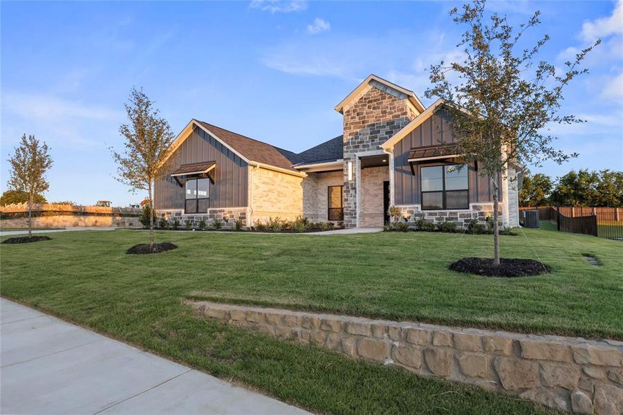 View of front of home with board and batten siding, stone siding, and roof with shingles
