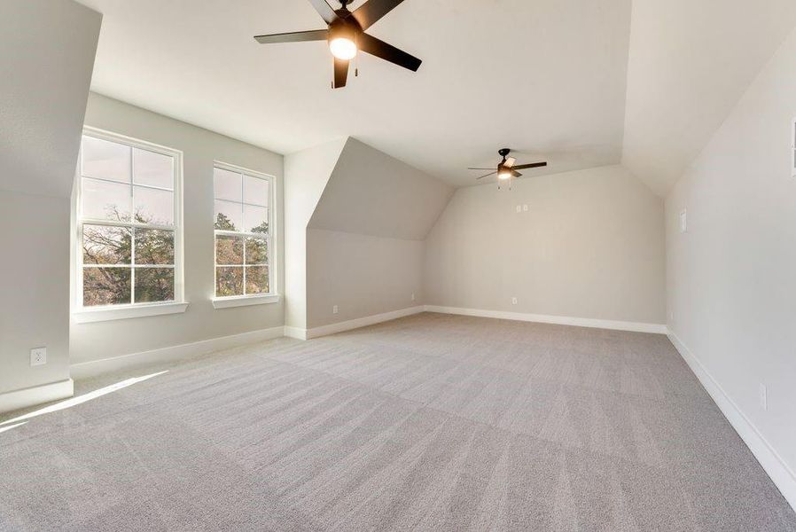 Bonus room with light carpet, ceiling fan, and vaulted ceiling