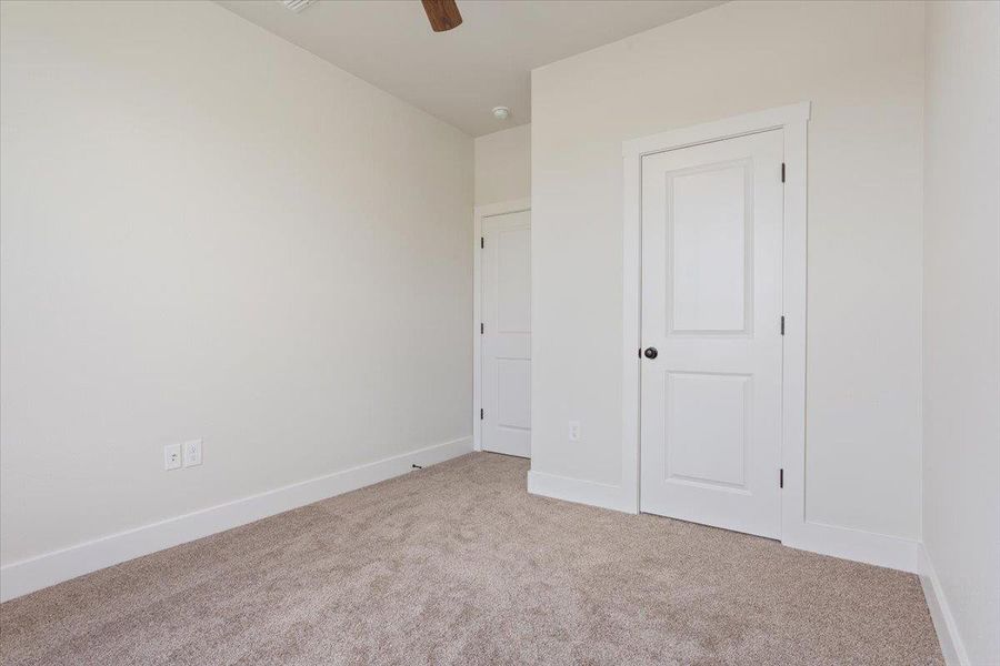 A spacious, neutral room offers a blank canvas for personalization, complete with soft carpeting and pristine white doors.